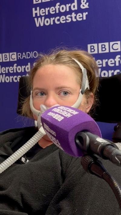 A woman in a radio station with an oxygen tube attached to her face