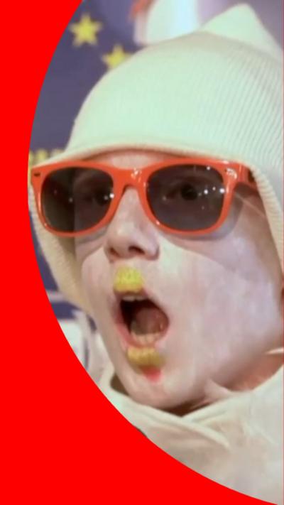 Person with a yellow hat, orange sunglasses and yellow paint on their lips.