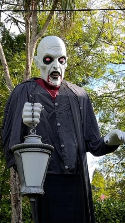 A ghostly figurine dressed in all black holding a lantern. 