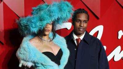 Rihanna wearing a pale blue coat and A$AP Rocky standing beside her in a navy suit