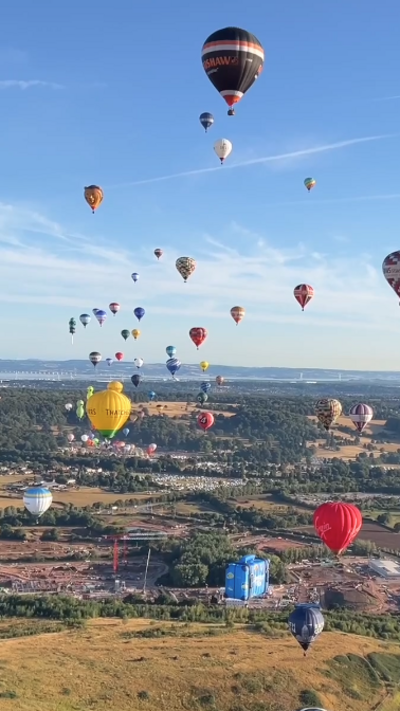 Lots of balloons hover over the landscape. 