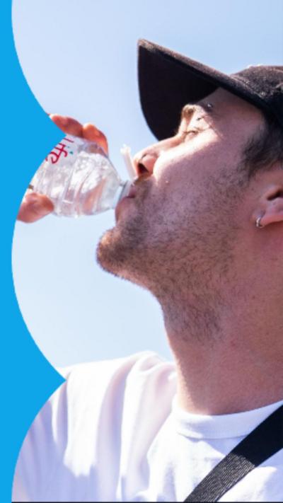 Man in white t-shirt and black cap drinks from bottle of water in front of Big Ben