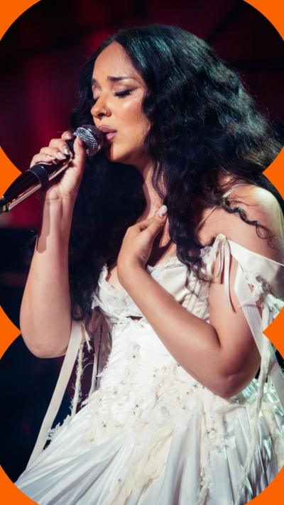 Jade holding a microphone and singing, with her eyes closed