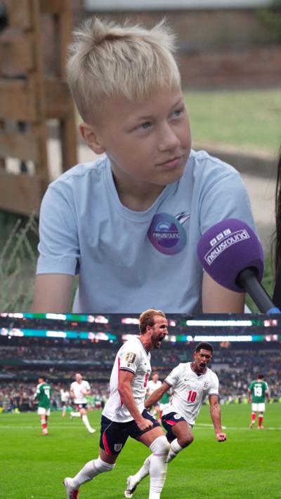 A young boy with blond hair and a blue top sits outdoors looking to the side with a purple BBC mic near him. Underneath shows an image of England football players celebrating.