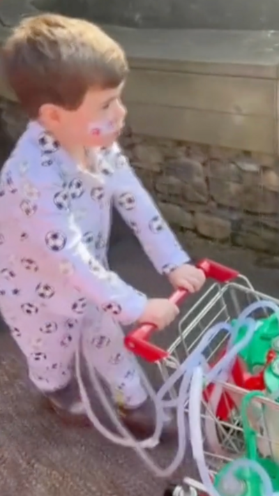 A 5-year-old outside pushing a shopping trolley