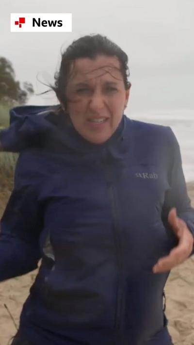 Katy Watson stood on a beach getting battered by strong winds