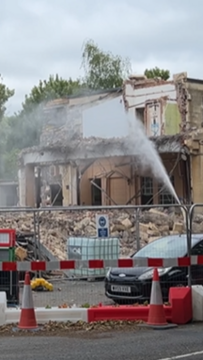 A hose is being sprayed at a demolished building