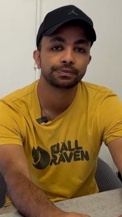 Man in a yellow shirt and black hat.