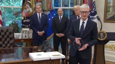TIm Cook holds a glass disc with the Apple logo cut out in the centre, while President Trump looks on behind him.