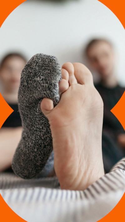 Two feet on a bed - one foot has a sock, the other one doesn't 