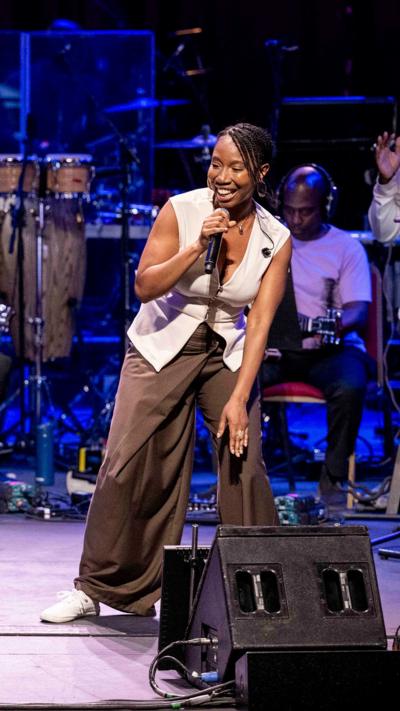 Female singer smiling and performing on a live concert stage