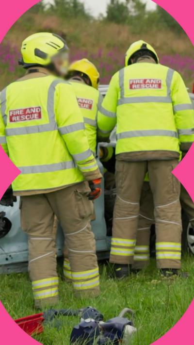 Ambulance drives on road with emergency lights on. Paramedics attend a man lying in a stretcher on the side of a road.