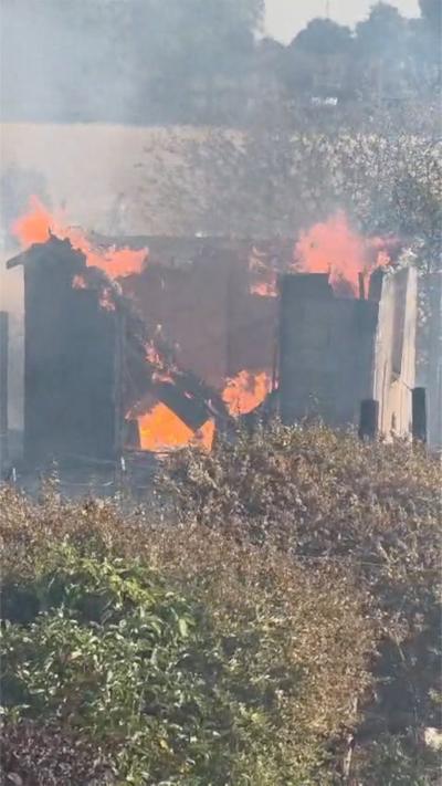 A shed is up in flames and smoke fills a back garden.