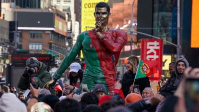 Fans gather around a statue of Cristiano Ronaldo.