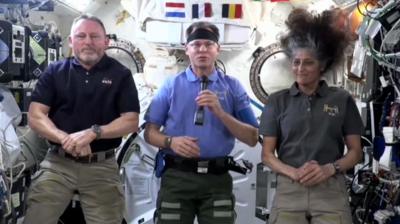 three astronauts talking to camera aboard the ISS