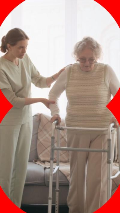 An older woman with a walking frame, being helped by a carer
