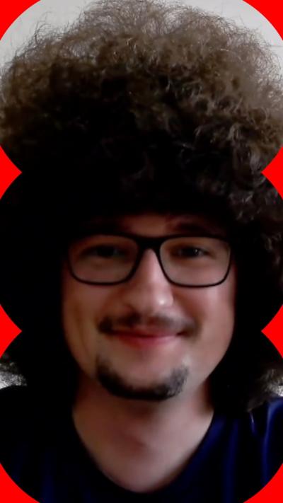 Manchester United fan Frank Ilett has large curly dark hair, bigger than his face, and is wearing glasses