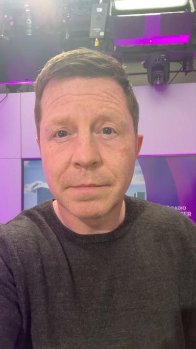 A political correspondent looks at the camera in a radio studio 