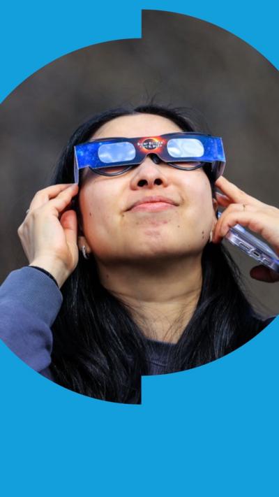 A woman observes the solar eclipse with an eclipse viewer, in New York in April 2024