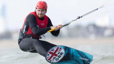 Team GB kitesurfer Connor Bainbridge standing on his board, competing