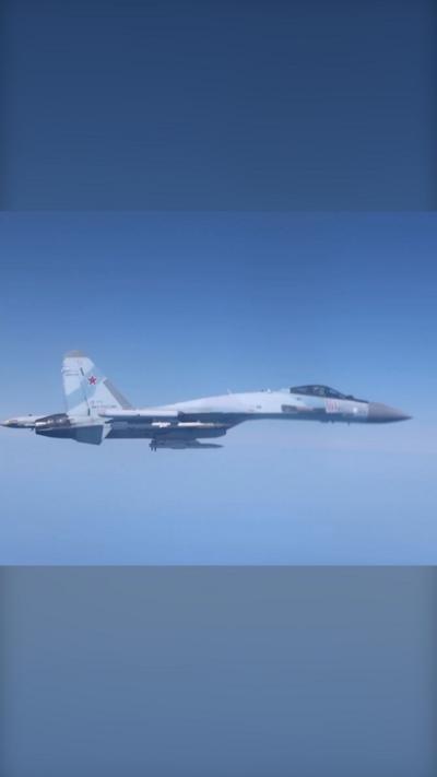 A grey Russian fighter jet is flying against a clear blue sky.
