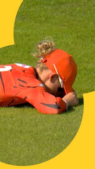 Phoebe Litchfield lies on the floor with her head buried after missing what would've been an excellent catch