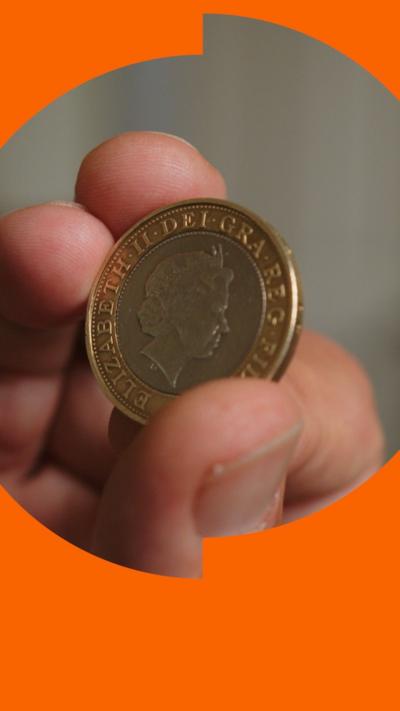 A close-up of a coin with a silver centre showing Queen Elizabeth II's head and an gold outer ring