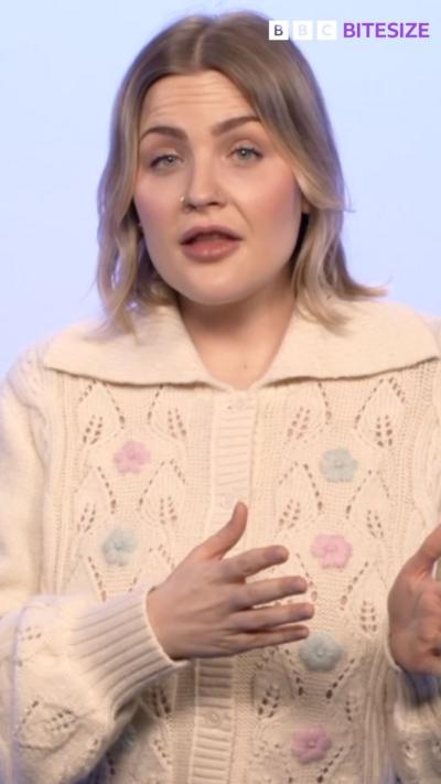 Mared Parry who is blonde and has a nose ring in a knitted cardigan in front of a pale blue background