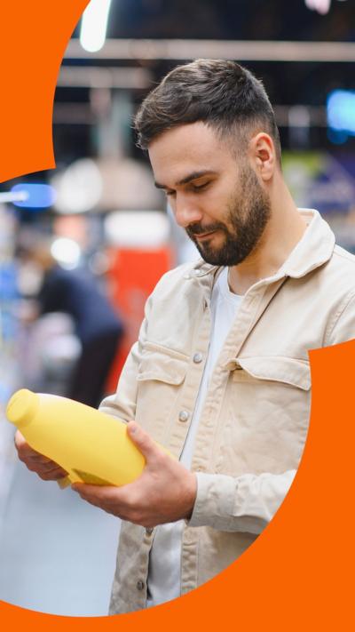 Man in a supermarket aisle looking at a yellow plastic bottle