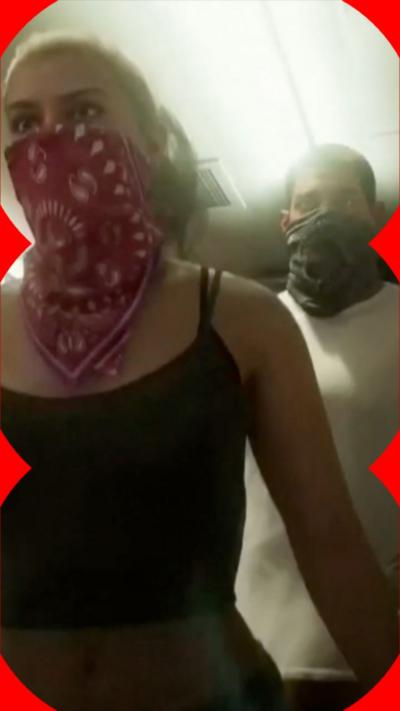 Still of GTA, a woman waring a red scarf over her mouth and a man behind her wearing a black scarf over his