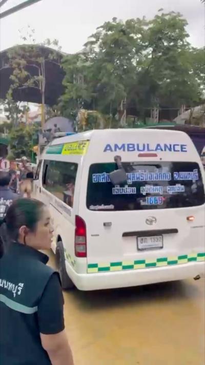 A man with a blue face mask stands in front of a Thai ambulance.