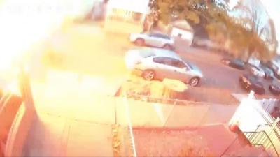 A large burst of fire is seen breaking out over a street with several cars