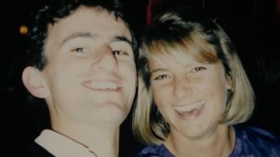 A film photograph of Tim Burman and Rosie Grant smiling. Tim has brown hair and Rosie has a blonde bob.