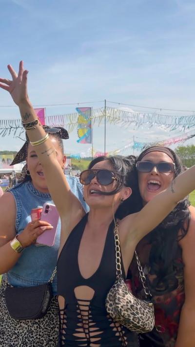 Three women smiling and waving their arms at the festival.