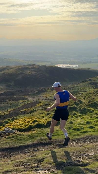 A man running down a hill on a sunny day.