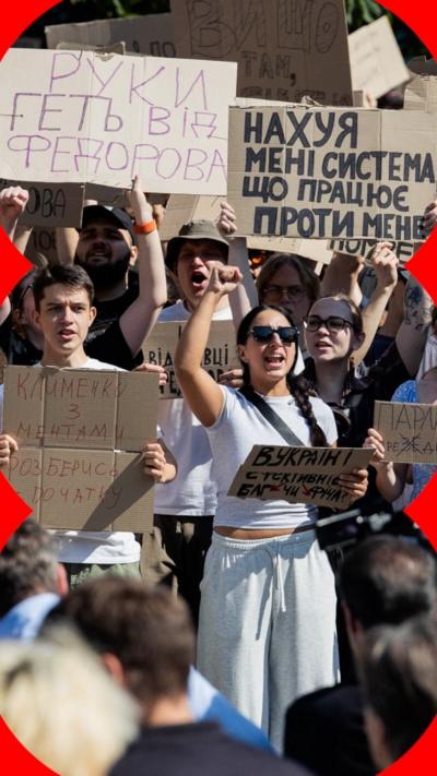 A group of Ukrainians protest. They are holding up signs with Cyrillic written on them.