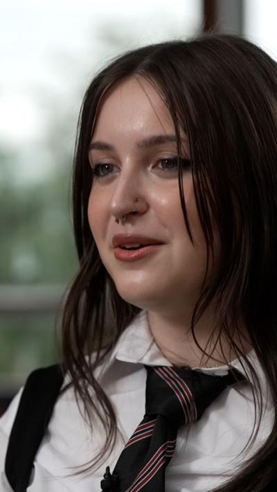 Tess - pupil with long dark hair wearing school uniform including tie and white shirt