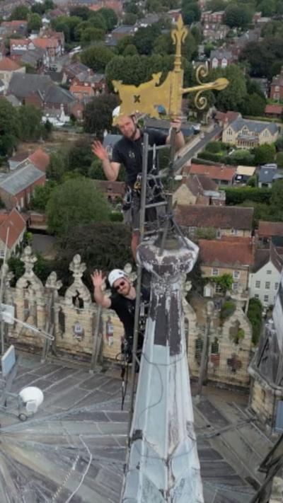 An aerial view of Lincoln Cathedral's central tower and pinnacles, towering above the city as maintenance workers carry out inspections high above the rooftops.