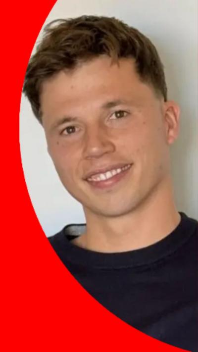 A man with short brown hair smiles at the camera