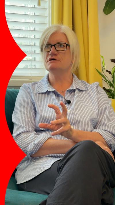 A woman wearing a striped shirt is sat on a sofa