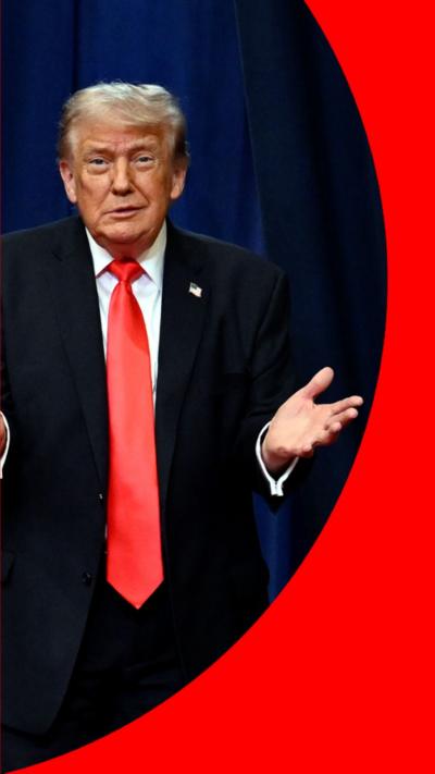 Donald Trump is wearing a black suit with a red tie