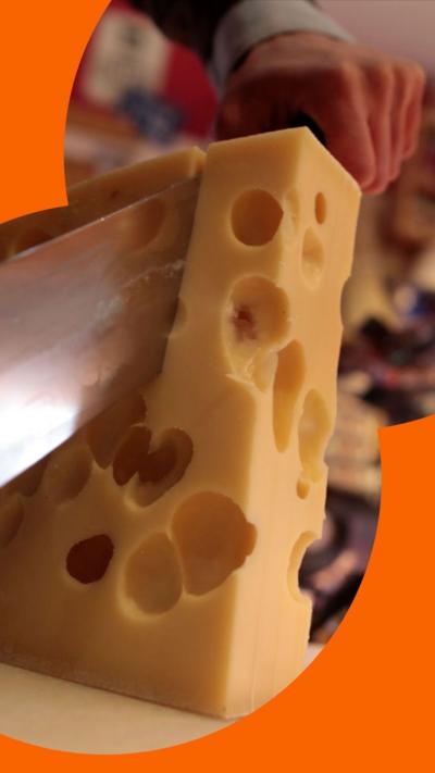 A slice of Swiss cheese with multiple holes. A knife cuts through it