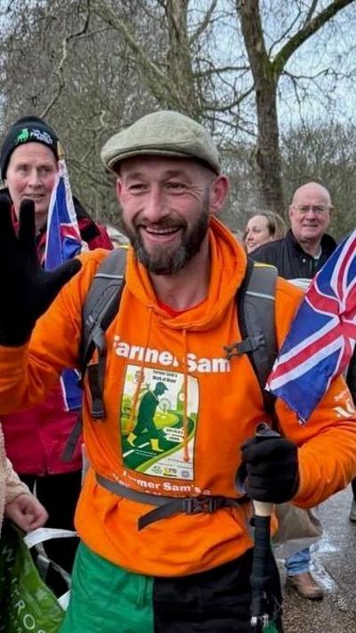 Man in green flat cap and orange hoodie on a walking challenge