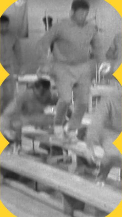 A black and white image showing men jumping up and down on gymnasium benches.