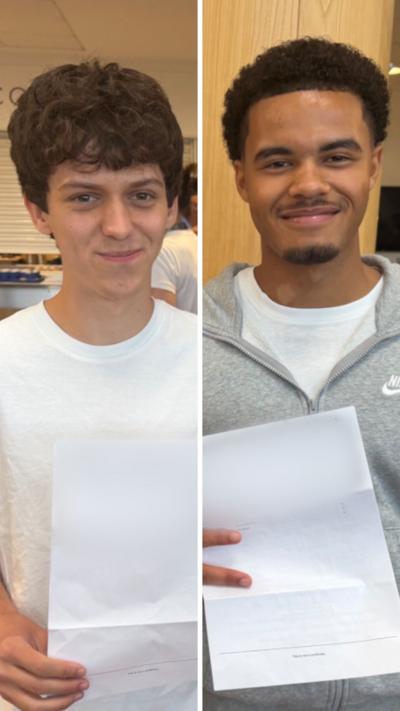 Oliver (left) in white t-shirt, Rhys (right) in grey hoodie, hold their exam results letters.