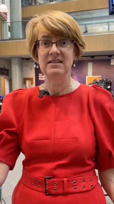 A woman with short red hair and glasses wearing a red dress 