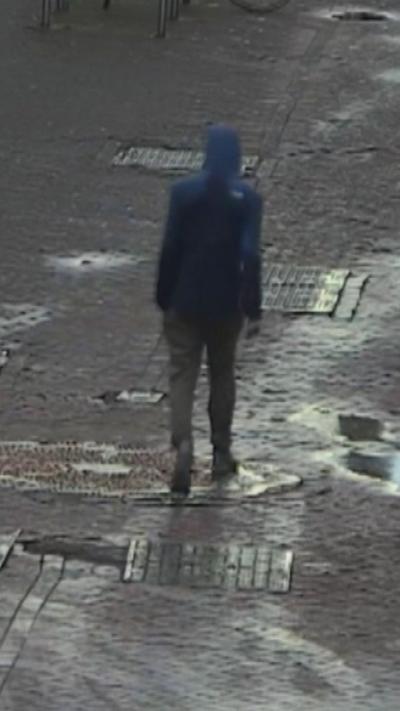 CCTV of a man in a dark hooded jacket, walking down an Edinburgh street