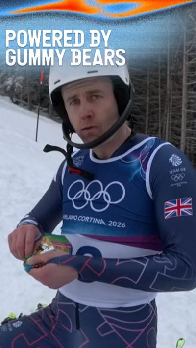 Dave Ryding eating a packet of gummy bears in Team GB ski gear on the slope