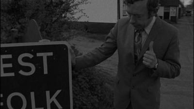 A Nationwide reporter standing beside a sign for West Suffolk