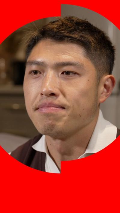 A man in a brown jumper and white shirt